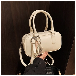 Detail der cremefarbenen Boston Bag mit geflochtenem Anhänger und Schultergurt