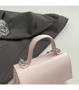 Detail of light pink leather handbag with silver chain hardware and durable handle