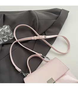 Close-up of pink leather handbag with metallic buckle and adjustable shoulder strap