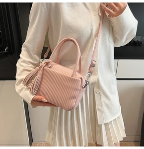 Pink lychee texture crossbody bag with pleats and tassel accessory worn by model