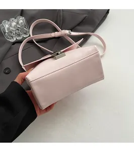 Close-up of the flat bottom and metallic lock on a light pink leather crossbody bag