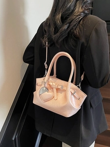Bolso bucket de cuero plisado rosa con asa y dije de corazón usado por modelo