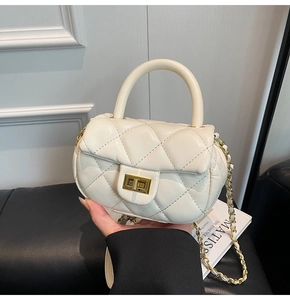 Dettaglio mini borsa trapuntata color crema con chiusura dorata e tracolla a catena