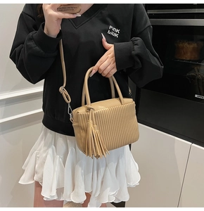 Caramel pleated crossbody bag with fringe detail shown on a model in a casual setting