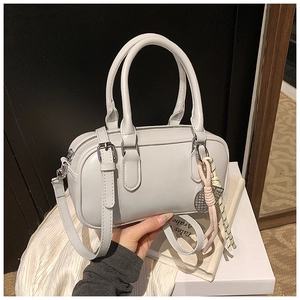 Gros plan d'un sac Boston gris clair avec pendentif tissé et bandoulière