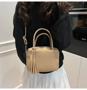Detail of beige pleated leather crossbody bag with tassel and adjustable shoulder strap