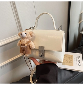 Minimalistische witte vierkante handtas met een schattige teddybeerbedel en slotje