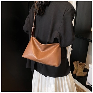 Sac Boston en cuir marron vue de profil porté avec un blazer élégant et chic