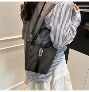 Detail of dark gray woven bucket bag with leather handles and silver twist-lock closure
