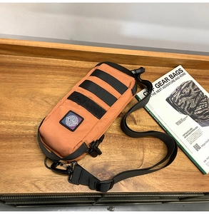Detail view of the brown tactical nylon chest bag with MOLLE webbing on a wooden surface