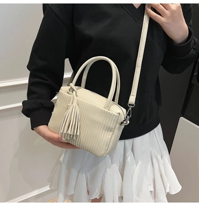 Detail of beige pleated stripe crossbody bag with side tassel and adjustable strap