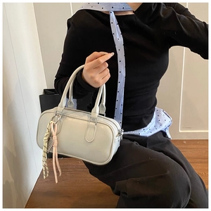 Nahaufnahme der cremeweißen Boston-Tasche aus Kunstleder mit gewebtem Riemen am Modell