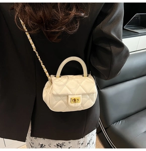 Borsa a tracolla bianca trapuntata con catena dorata indossata su un blazer nero