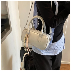 Détail du sac Boston gris clair avec pendentif nœud tressé et bandoulière réglable