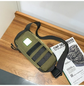Close-up of military green tactical chest bag with reflective patch on wooden surface