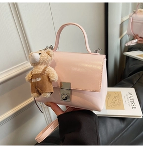 Detail van roze lederen handtas met zilveren gesp en bruine teddybeer-bedeltje