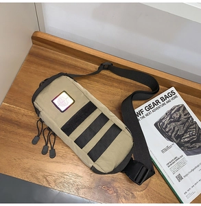 Macro detail of khaki tactical chest bag with MOLLE webbing and reflective patch on wood