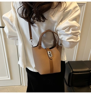 Detail der beigen Bucket Bag mit Flechtstruktur, silbernem Metallverschluss und Lederriemen