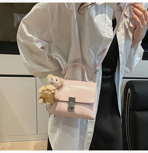 Detail van lichtroze leren handtas met zilveren gesp en schattige teddybeerhanger