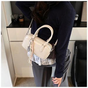 Gros plan d'un sac polochon rétro crème avec bijou de sac porté par un mannequin