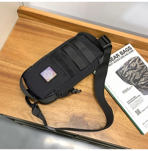 Tactical black chest bag on wood desk with MOLLE webbing and velcro detail