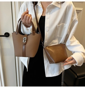 Detail of a brown woven bucket bag with leather handle and smooth crossbody handbag