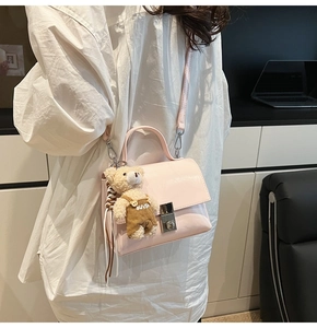 Roze crossbodytas met metalen slot en een schattige pluchen beer aan een wit shirt