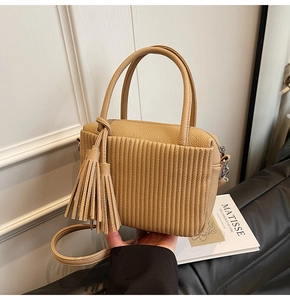 Detail of beige pleated leather crossbody bag with fringe tassel and top handles