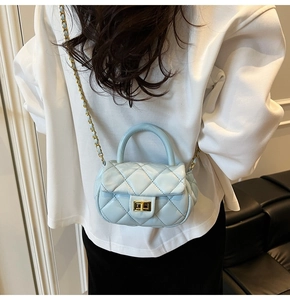 Mini borsa trapuntata azzurra indossata da una modella con catena dorata e chiusura a vite