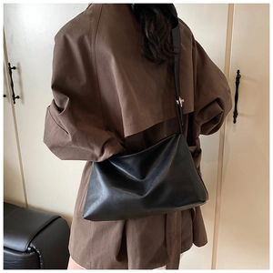 Détail du grand sac à bandoulière en cuir souple noir montrant la texture et la boucle en métal