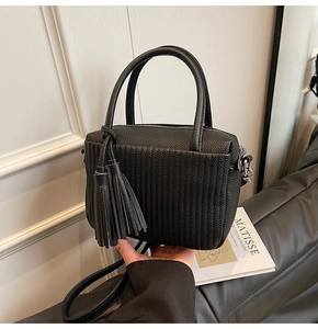Detail of black pebbled leather crossbody bag with pleated stripes and a long tassel