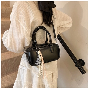 Detailansicht einer schwarzen Boston-Tasche aus Leder mit einem Schachbrett-Anhänger