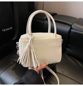 Detail of off-white pleated leather mini bag with cylindrical handle and tassel charm