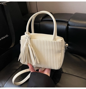 Detail view of cream pleated crossbody bag showing vertical wavy texture and silver hardware