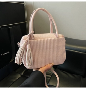 Detail view of pink crossbody bag with accordion pleats and elegant double tassels