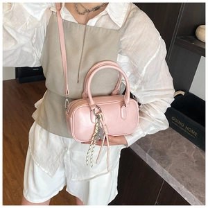 Detail der rosa Boston-Handtasche mit verstellbarem Riemen und Metall-Buchstabenanhänger