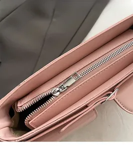 Gros plan sur la fermeture éclair argentée d'un sac à main rose à texture litchi