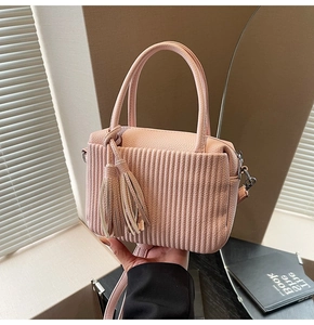 Detailed macro of pink lychee leather handbag featuring vertical pleats and twin tassels
