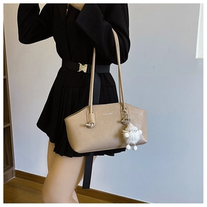 Detail of beige faux leather shoulder bag with plush charm and fashion logo print