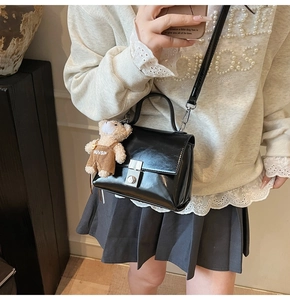 Glanzende zwarte crossbody tas met zilveren slot en schattige pluche berenhanger