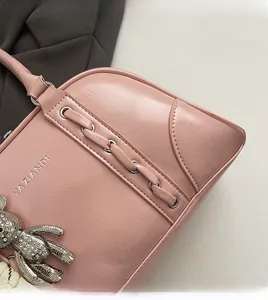 Détail d'un sac bowling rose en similicuir avec logo et breloque ours brillante