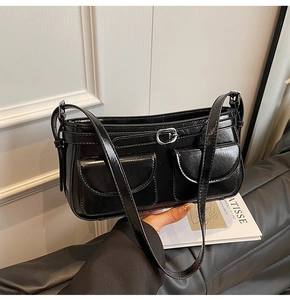 Détail d'un sac d'épaule en cuir verni noir avec doubles poches à rabat et boucles argentées