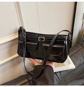 Détail du sac sous le bras noir verni avec deux poches et boucle en métal argenté