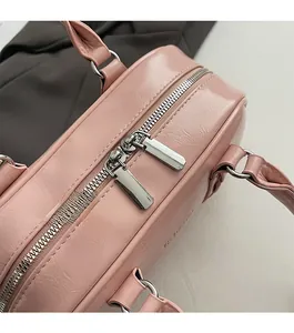 Détail des doubles fermetures éclair argentées sur le sac bowling rose en similicuir souple
