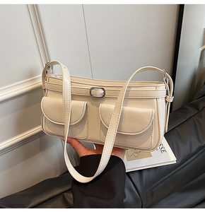 Détail d'un sac sous les aisselles crème montrant le cuir synthétique et la boucle argentée