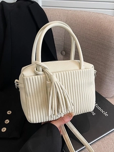 Chic cream white crossbody bag with vertical pleats and tassel charm in lifestyle scene