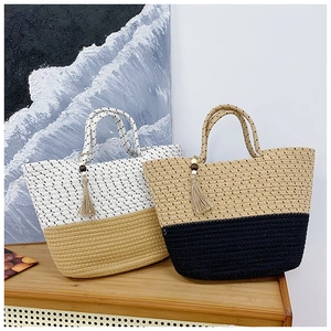 Close-up of woven straw tote bags with tassel charms and thick rope handles for beach