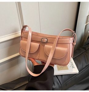 Détail du sac sous le bras en cuir rose brillant avec deux poches frontales et boucles en métal