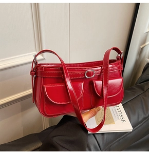Gros plan détaillé d'un sac sous le bras en cuir rouge brillant avec deux poches et boucles