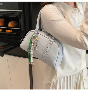Détail du sac à main en cuir bleu clair avec détails tressés et breloque ours sertie